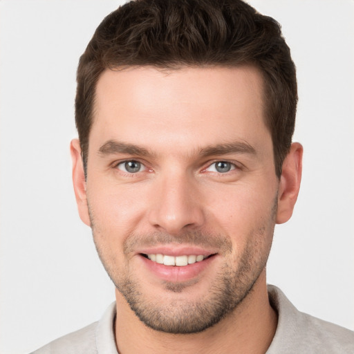 Joyful white young-adult male with short  brown hair and grey eyes