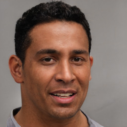 Joyful latino young-adult male with short  brown hair and brown eyes