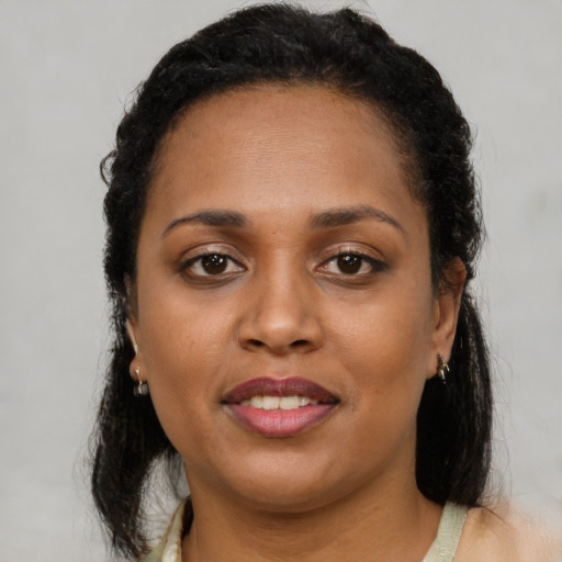 Joyful black young-adult female with long  brown hair and brown eyes