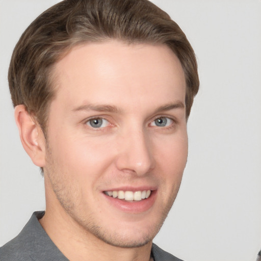 Joyful white young-adult male with short  brown hair and grey eyes