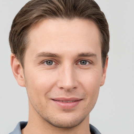 Joyful white young-adult male with short  brown hair and grey eyes