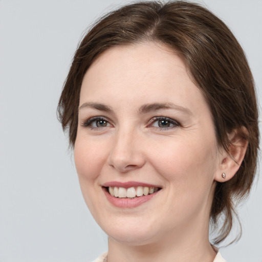 Joyful white young-adult female with medium  brown hair and grey eyes