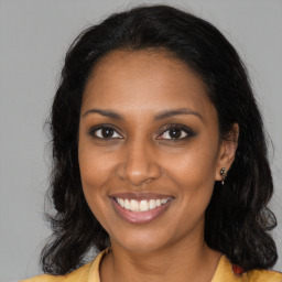 Joyful black young-adult female with long  brown hair and brown eyes