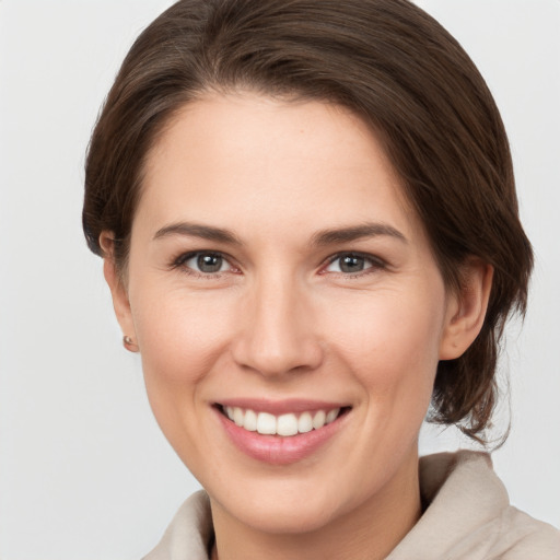 Joyful white young-adult female with medium  brown hair and grey eyes