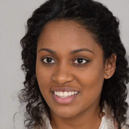 Joyful black young-adult female with long  brown hair and brown eyes