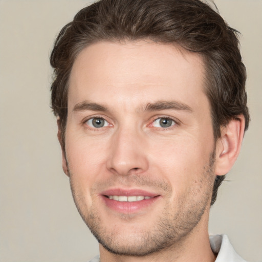 Joyful white young-adult male with short  brown hair and grey eyes