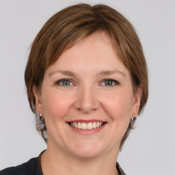 Joyful white young-adult female with medium  brown hair and grey eyes