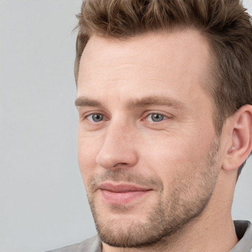 Joyful white young-adult male with short  brown hair and grey eyes