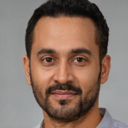 Joyful latino young-adult male with short  black hair and brown eyes