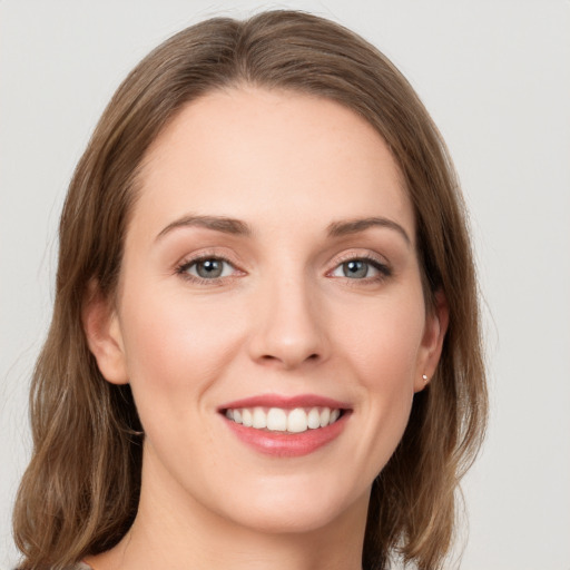 Joyful white young-adult female with medium  brown hair and grey eyes