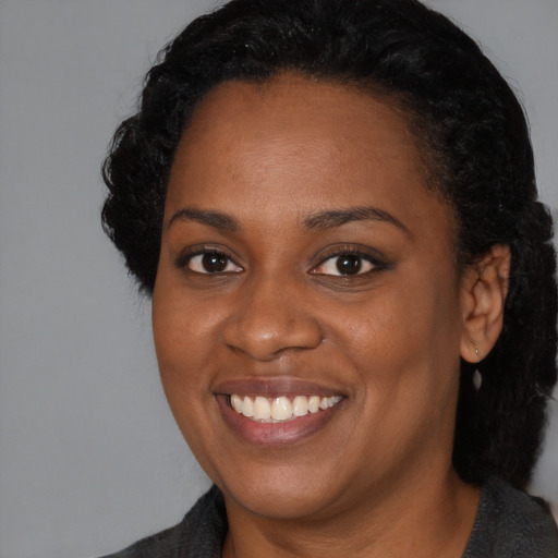 Joyful black young-adult female with medium  black hair and brown eyes