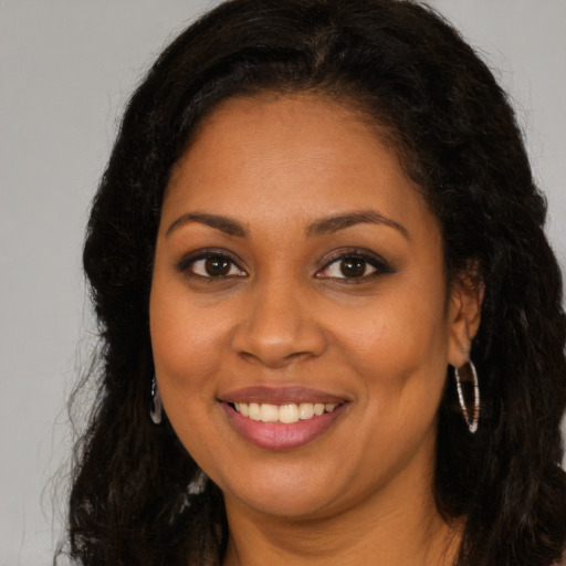 Joyful black young-adult female with long  brown hair and brown eyes