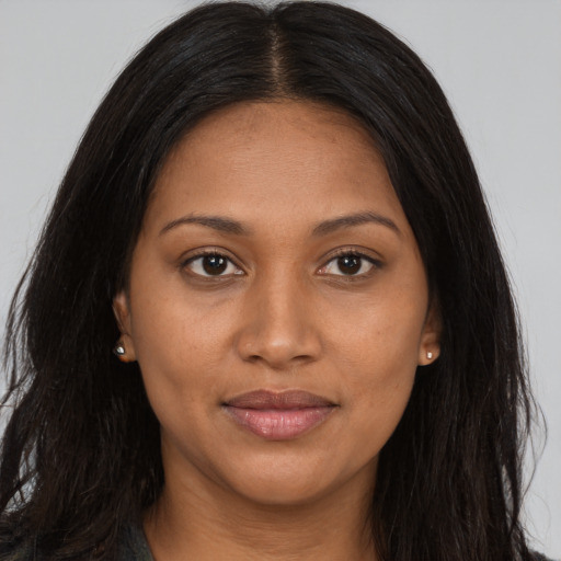 Joyful black young-adult female with long  brown hair and brown eyes