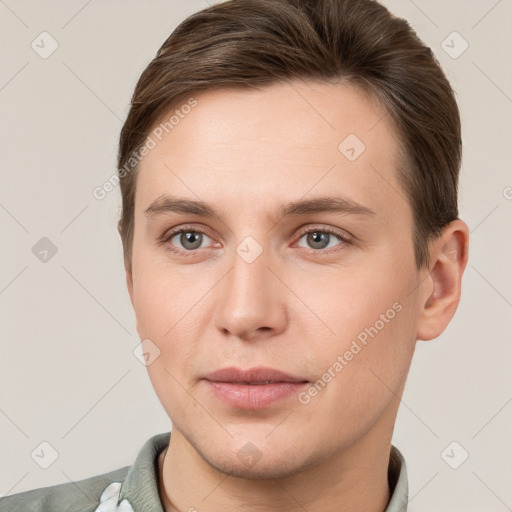 Joyful white young-adult male with short  brown hair and grey eyes