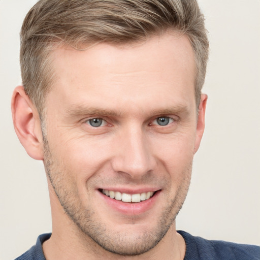 Joyful white young-adult male with short  brown hair and blue eyes