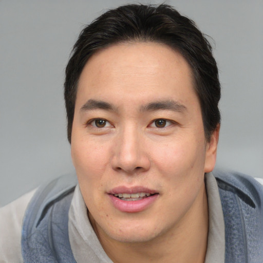 Joyful asian young-adult male with short  brown hair and brown eyes