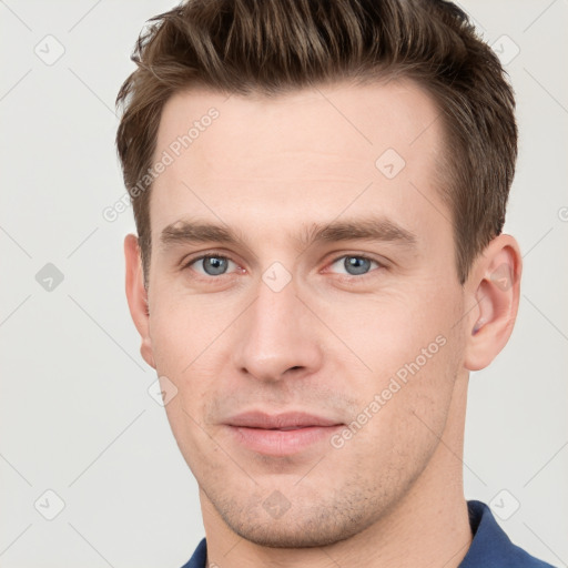 Joyful white young-adult male with short  brown hair and grey eyes