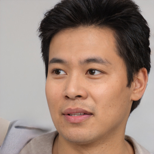 Joyful asian young-adult male with short  brown hair and brown eyes
