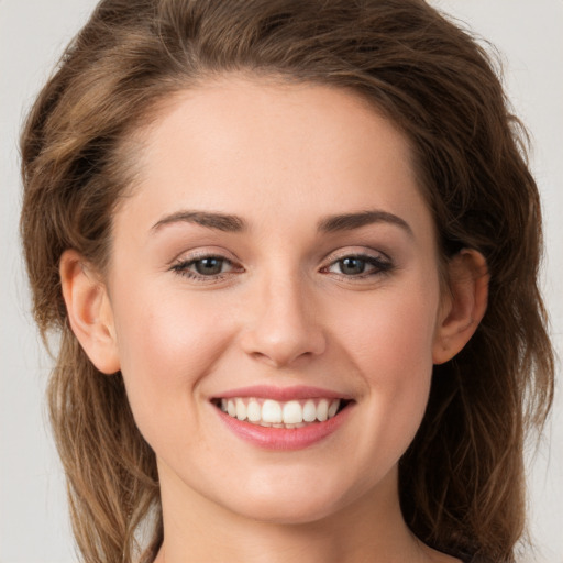 Joyful white young-adult female with long  brown hair and green eyes