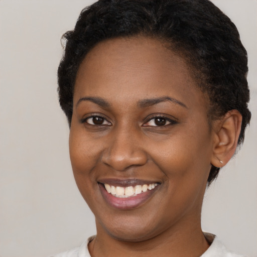 Joyful black young-adult female with short  brown hair and brown eyes