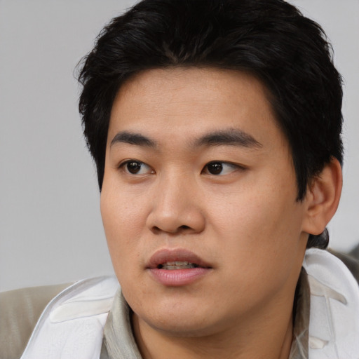 Joyful asian young-adult male with short  black hair and brown eyes