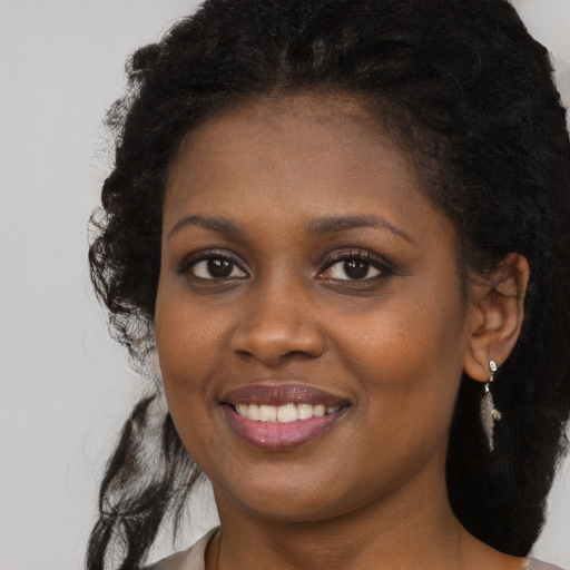 Joyful black young-adult female with long  brown hair and brown eyes