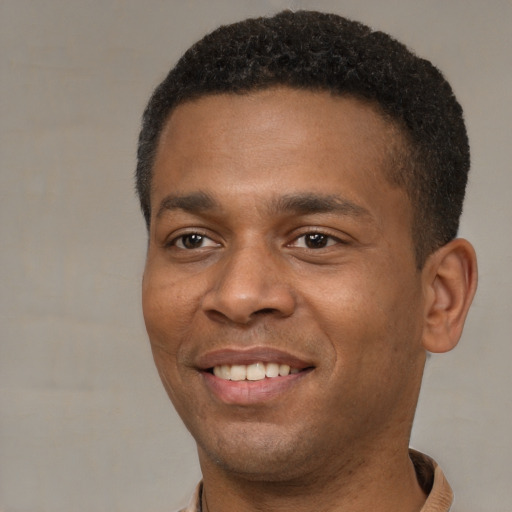 Joyful black young-adult male with short  brown hair and brown eyes