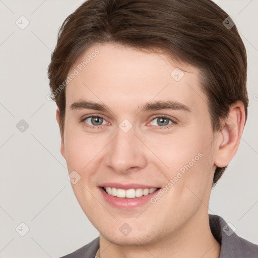 Joyful white young-adult male with short  brown hair and grey eyes