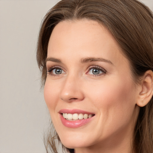 Joyful white young-adult female with long  brown hair and grey eyes