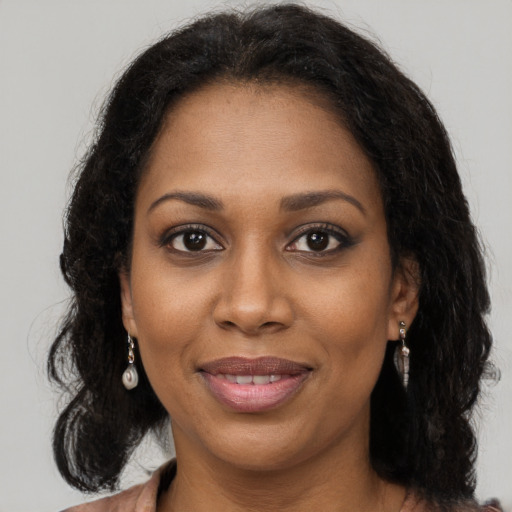Joyful black adult female with long  brown hair and brown eyes