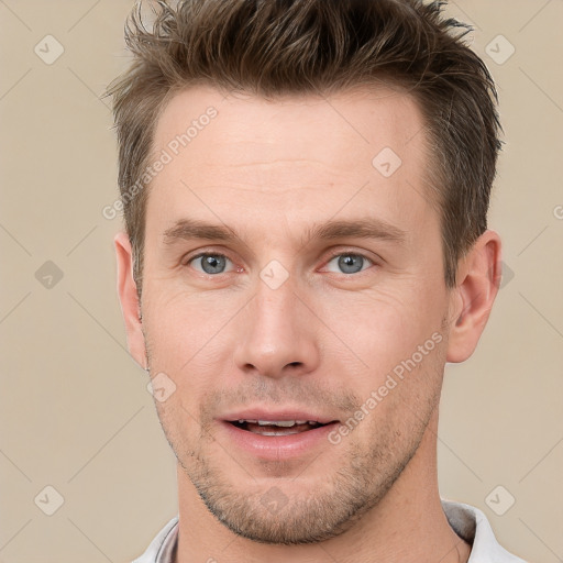 Joyful white young-adult male with short  brown hair and grey eyes