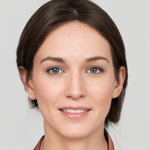 Joyful white young-adult female with medium  brown hair and grey eyes