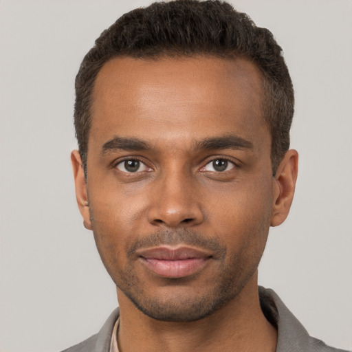 Joyful black young-adult male with short  brown hair and brown eyes