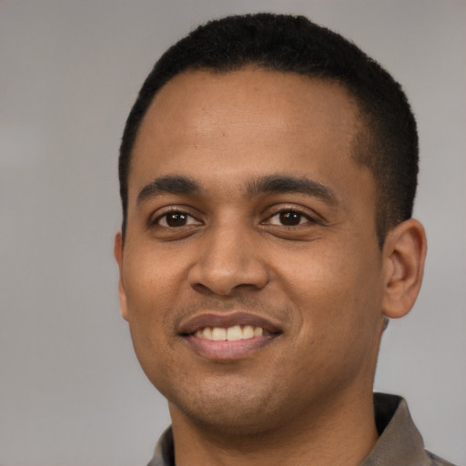Joyful black young-adult male with short  black hair and brown eyes