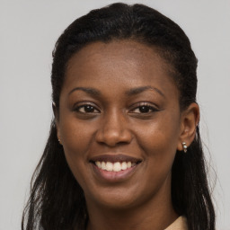 Joyful black young-adult female with long  brown hair and brown eyes