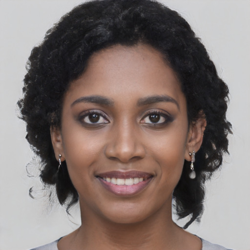 Joyful black young-adult female with long  black hair and brown eyes