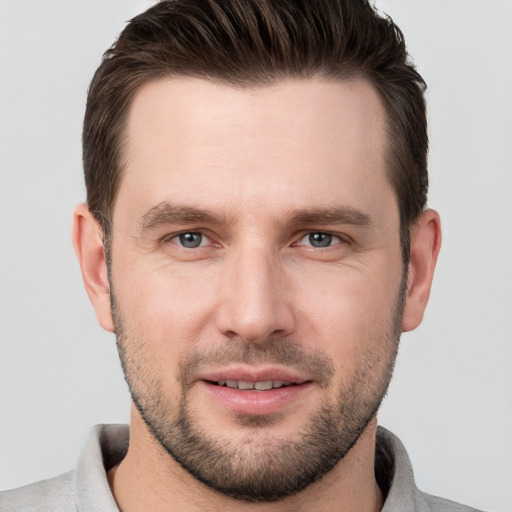 Joyful white young-adult male with short  brown hair and grey eyes