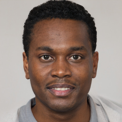 Joyful black young-adult male with short  black hair and brown eyes