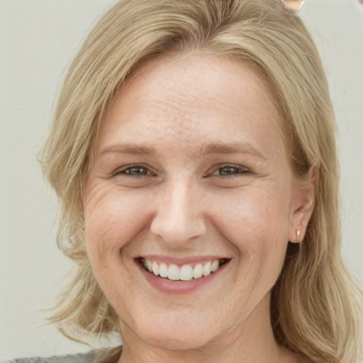 Joyful white young-adult female with long  blond hair and green eyes