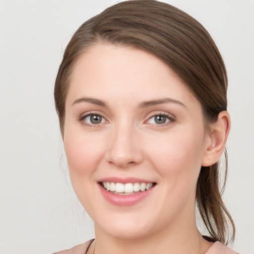 Joyful white young-adult female with medium  brown hair and grey eyes