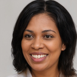 Joyful black young-adult female with long  brown hair and brown eyes