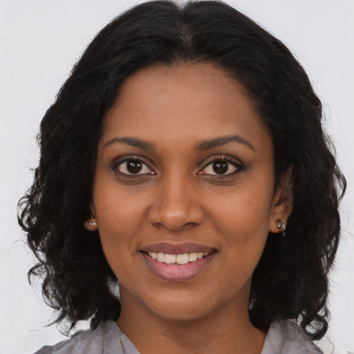 Joyful black young-adult female with long  brown hair and brown eyes