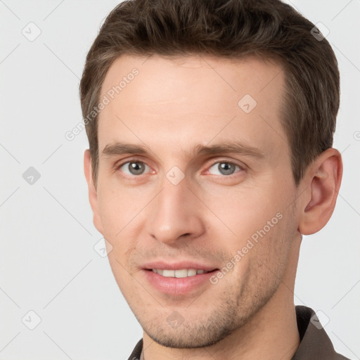 Joyful white young-adult male with short  brown hair and grey eyes