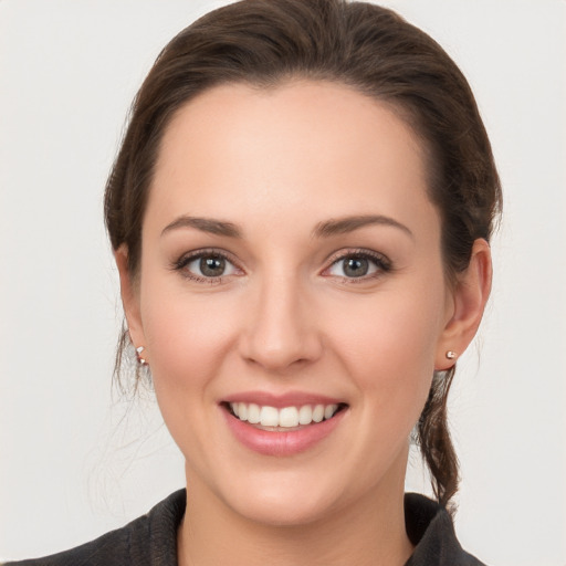 Joyful white young-adult female with medium  brown hair and grey eyes