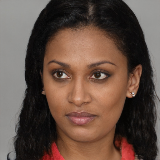 Joyful black young-adult female with long  brown hair and brown eyes
