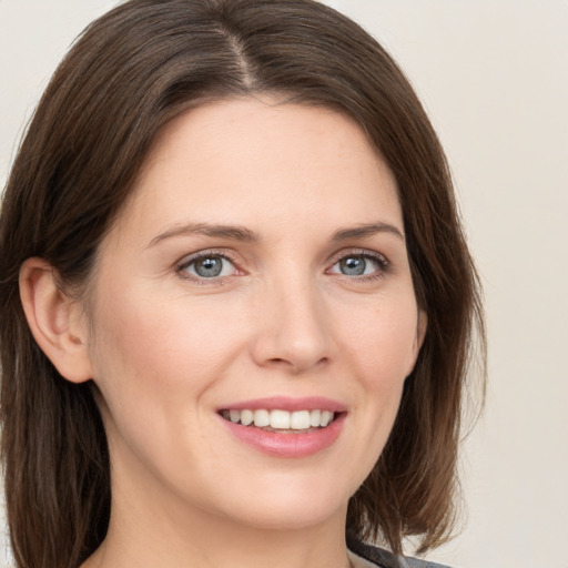 Joyful white young-adult female with long  brown hair and grey eyes