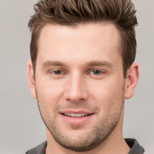 Joyful white young-adult male with short  brown hair and grey eyes