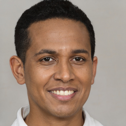 Joyful latino young-adult male with short  black hair and brown eyes