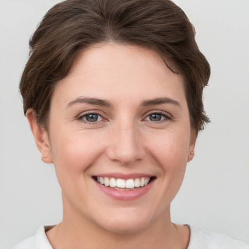 Joyful white young-adult female with short  brown hair and grey eyes