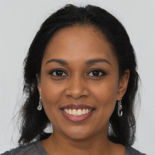 Joyful black young-adult female with long  brown hair and brown eyes